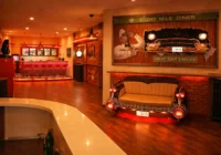 Cremefarbenes Bel-Air-Autosofa vor beleuchtetem Oldtimer-Wandbild und roter Dinerbar