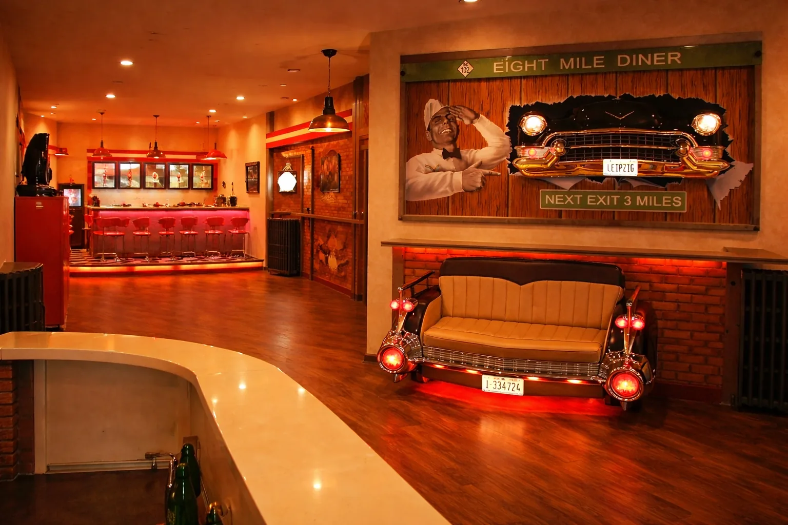 Cremefarbenes Bel-Air-Autosofa vor beleuchtetem Oldtimer-Wandbild und roter Dinerbar