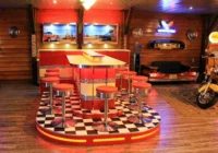 Rote Dinerbar mit Barhockern, Sitzbank und Motorrad in einer Oldtimergarage