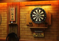 Dartscheibe und ausgewählte Vintage-Dekoration an einer dunkel gestalteten Garagenwand