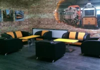 Lounge mit schwarzen und cremefarbenen Sofas vor einem grossformatigen Eisenbahn-Wandbild