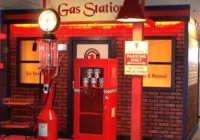 Rote Tankstellenkulisse mit Zapfsäule, Werkstatttor und Retro-Werbung