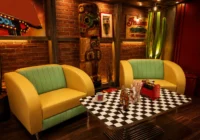 Gelbe und türkise Retro-Sofas mit Schachbretttisch, Kaktus und Tiki-Figur