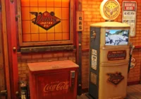 Werkstatt- und Tankstellenkulisse mit Holztüren, Zapfsäule und roter Coca-Cola-Truhe