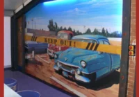 Gerahmtes Wandbild mit blauem klassischem Fahrzeug vor einer amerikanischen Strassenszene