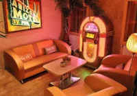 Gemütliche Retro-Lounge mit schwarzen Ledersofas, Couchtisch und Musikbox