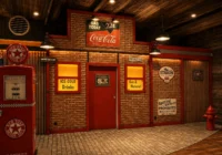 Backsteinfassade einer alten Tankstelle mit roten Garagentoren, Tanksäule und Coca-Cola-Schild