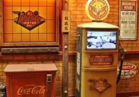 Nostalgische Tanksäule mit Bildschirm neben einer roten Coca-Cola-Truhe