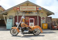 Motorrad vor einer nostalgischen Gas-Station-Kulisse mit Tanksäulen