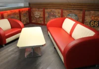 Zwei rote Diner-Sitzbänke mit weissem Tisch in einer privaten Car Lounge